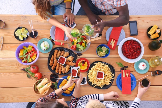 Top view of group of people having dinner together while sitting at wooden table Food on the table People eat fast food