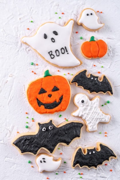 Top view of Halloween festive decorated icing gingerbread sugar cookies on white background with copy space and flat lay layout.