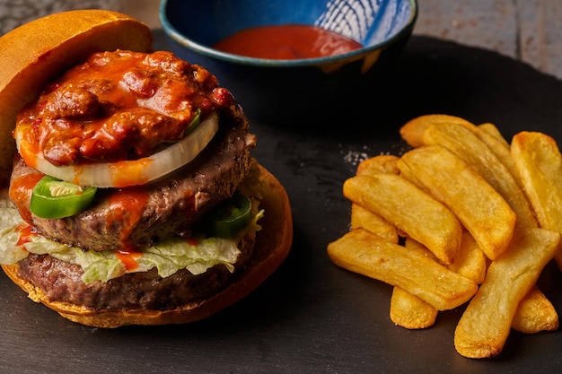 Top view hamburger with fries onion chili with meat and jalapenos barbecue sauce dark style food