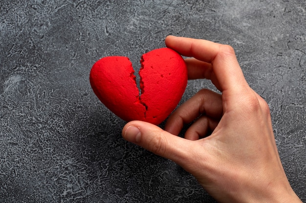 Photo top view hand holding broken red heart