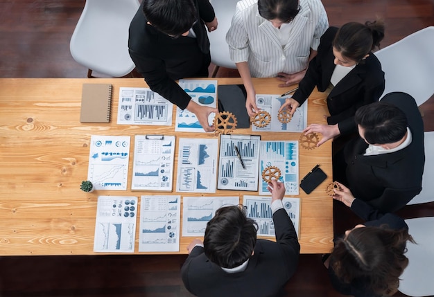 Top view hand holding gear by group of businesspeople on table in harmony office