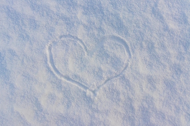 Top view handdrawn a heart shape on natural pure white soft snow surface in a cold weather day Symbol of love in winter holiday season