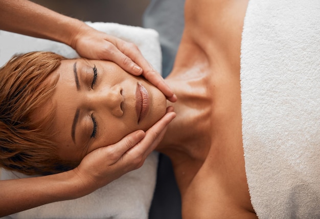 Top view hands and facial massage at spa for beauty treatment or relax Face skincare and wellness of black woman at peace relaxing release stress or tension with eyes closed at luxury resort