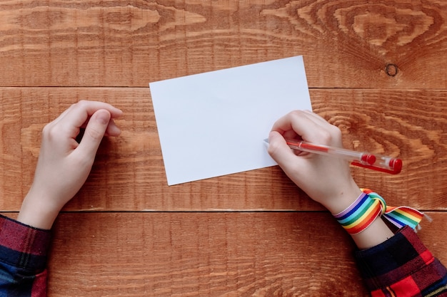 Top view of hands writing a note on wooden background