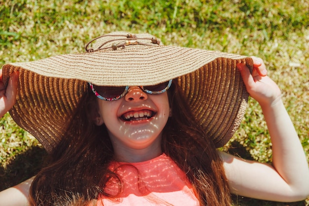 Top view of a happy girl smiling and lying on the green grass on a summer day in the park