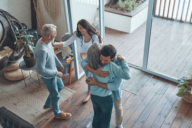 Top view of happy senior parents meeting young couple inside the house