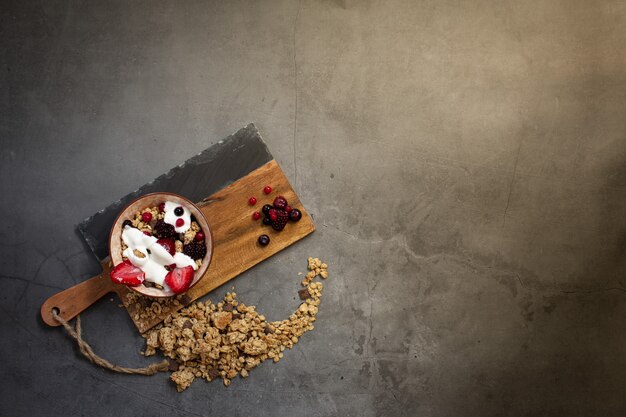 Top view of a healthy breakfast with muesli, yogurt and seasonal berries on a concrete background