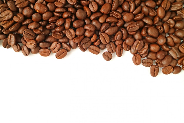 Top view of heap of roasted coffee beans isolated on white background