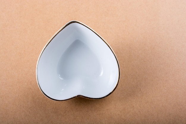 Top view of a heart shaped tin bowl on a brown surface