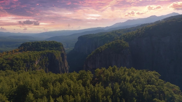 Top view of high rocks in mountainous area Sunset sky Pink purple clouds The tops of the trees High quality photo