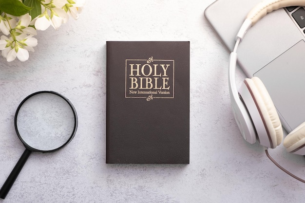 Top View of Holy Bible on working table with headphones Bible study and search online concept