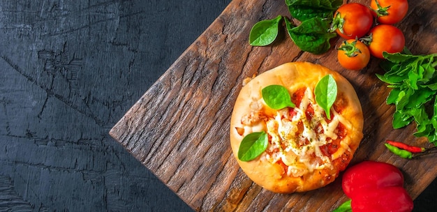 Top view of home made pizza vegetables ingredients on a Black wooden background Pizza is cooking