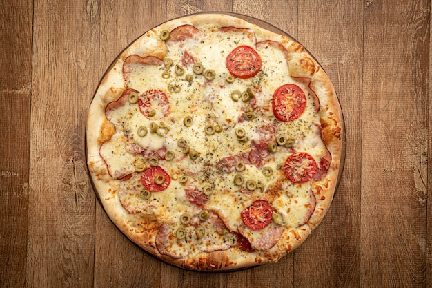 Top view of homemade pizza with tomato, olive, cheese and other ingredients.