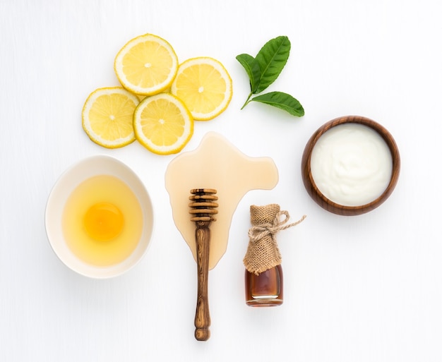 Top view of honey yogurt and lemon on wooden white background