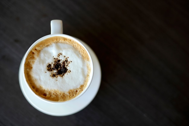 Top view hot cappuccino in white cup on wooden table