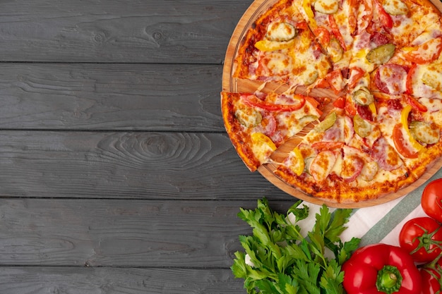 Top view of hot pizza on black wooden table