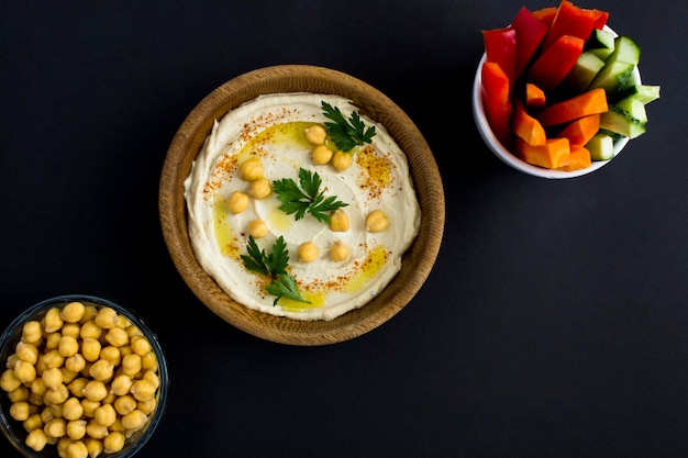 Top view of hummus in the bowl and vegetable on the black background Closeup Copy space