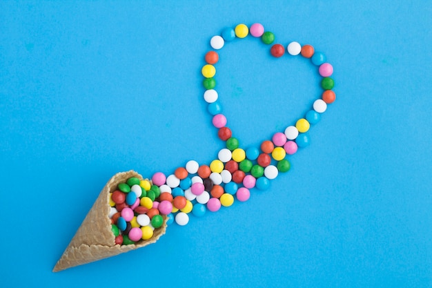 Top view of ice cream cone with candy on the blue