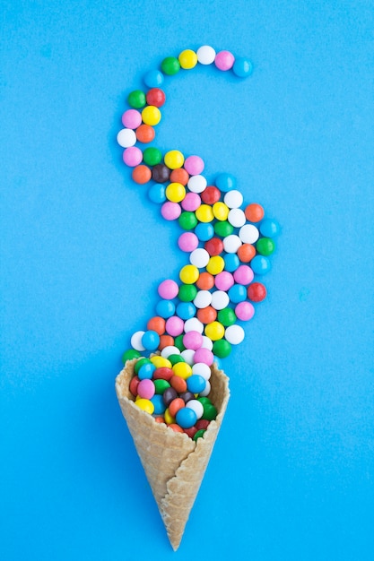 Top view of ice cream cone with candy on the blue