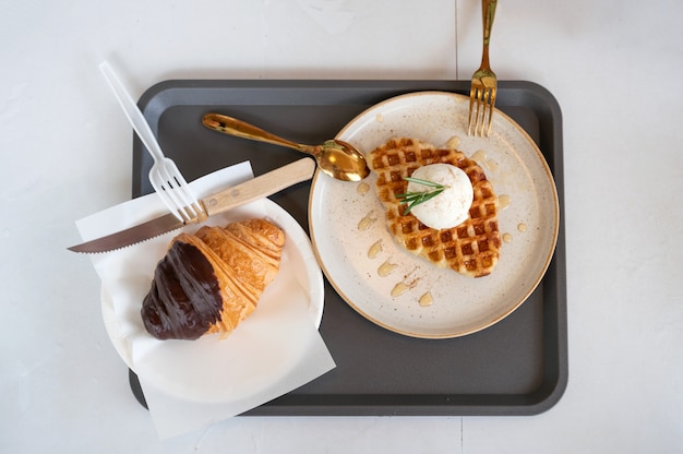 Top view of Ice cream vanilla with waffle and chocolate croissant and brass spoon on white dish