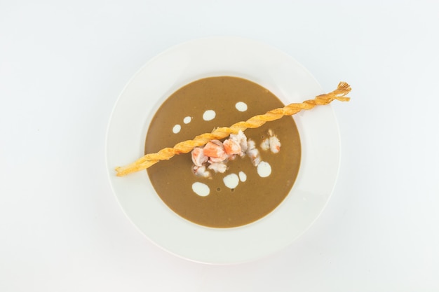 Top view image of Cream soup with crab meat and bread stick on white background