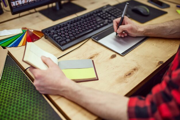 Top view image of graphic designer working with graphic tablet using color palette making sketches