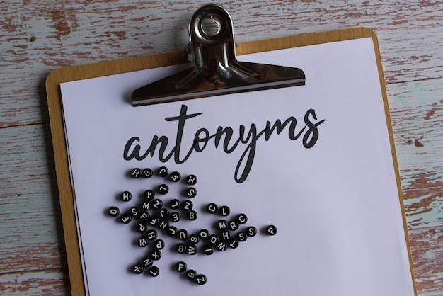 Top view image of paper clipboard with text antonyms and alphabet beads