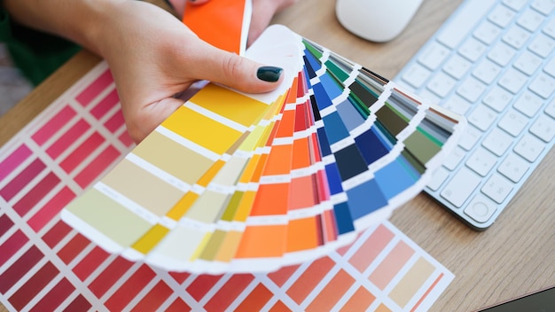 Top view of interior designer holding fan of colourful samples in hand woman searching proper