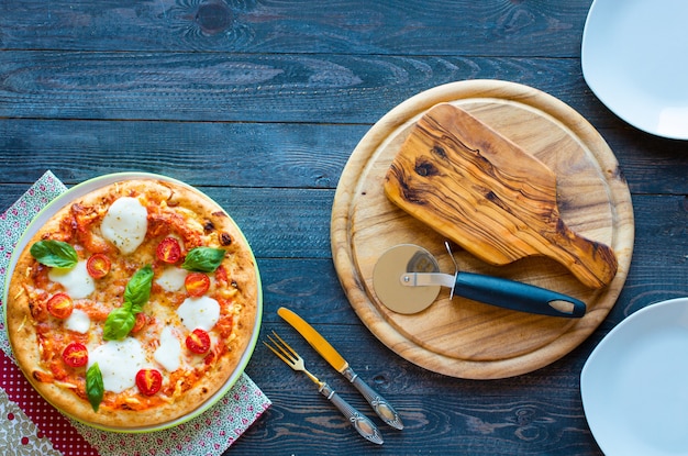 Top view of italian classic pizza margherita over a wooden table with toppings