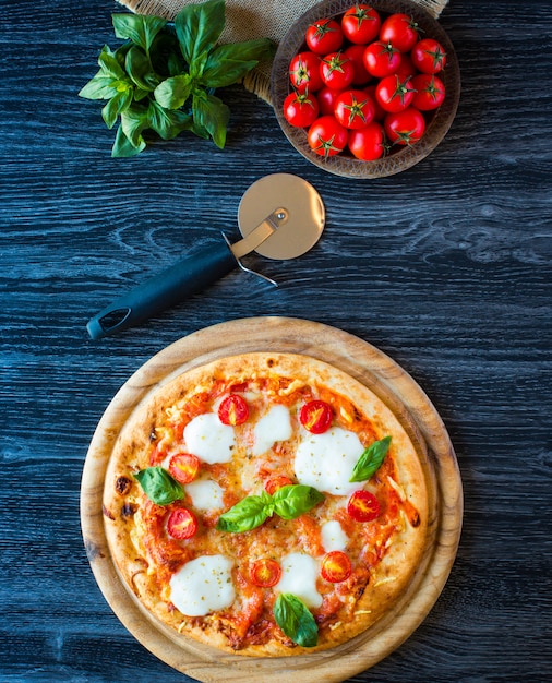 Top view of italian classic pizza margherita over a wooden table with toppings