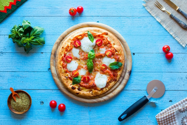 Top view of italian classic pizza margherita over a wooden table with toppings