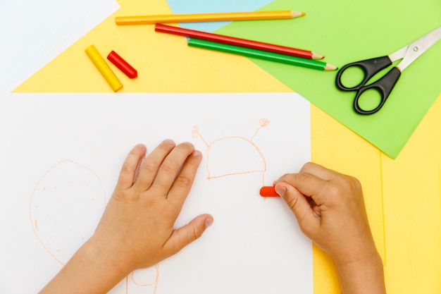 Top view of kids hands paiting with crayons Indoor activity