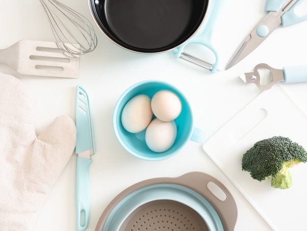 top view of kitchen room concept with kitchenware, egg and vegetables on white table background.