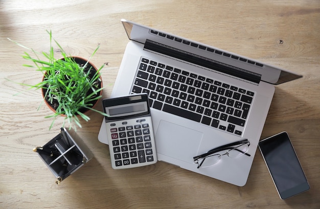 Top view.laptop, calculator and smartphone on a wooden table