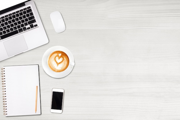 Top view laptop computer or notebookmobile phone and cup of latte art coffee on wooden table