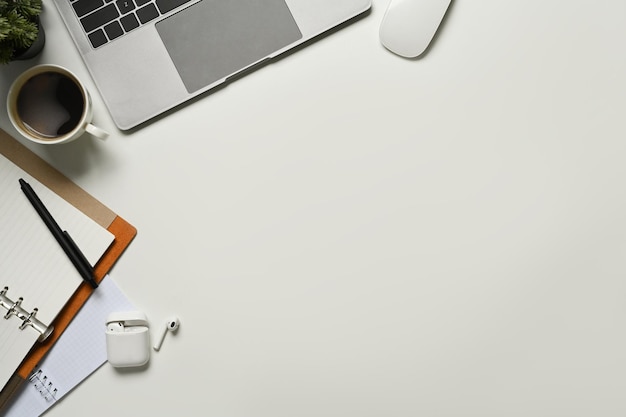 Photo top view of laptop computer notepad cup of coffee and earphone on white working desk