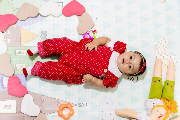 Photo top view of a latina baby girl looking at camera lying on a baby mat