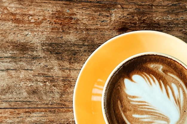 Top view of a latte art coffee on old wooden table