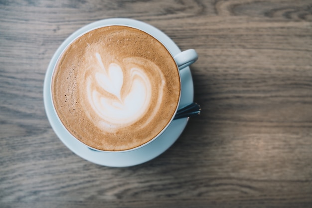 Top view of Latte hot coffee in a white cup with latte art on wooden table background