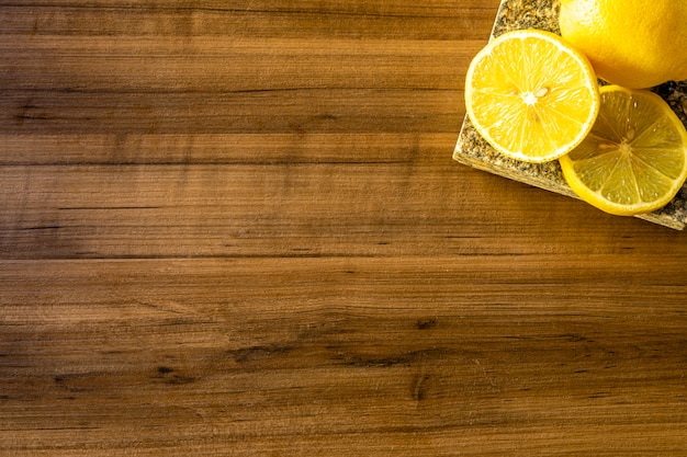 Top view of lemon and green leaves on wooden table