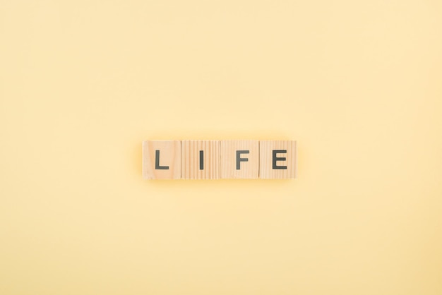 Top view of life lettering made of wooden cubes on yellow background