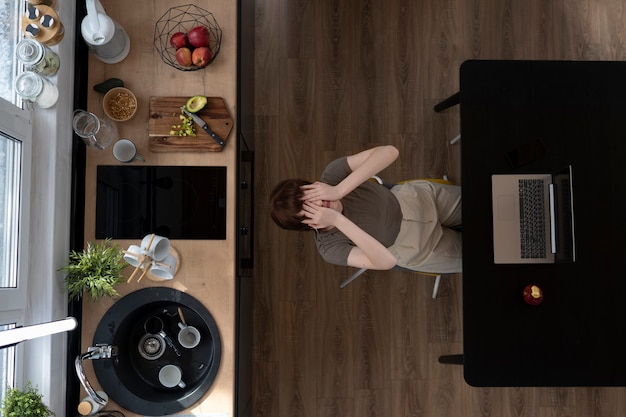 Top view lonely woman with laptop in kitchen