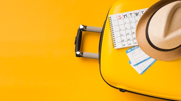 Top view of luggage with hat and calendar and copy space