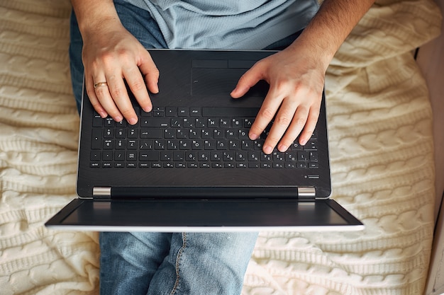 Top view of male hands using modern laptop, close up of young man working at home and using notebook computer