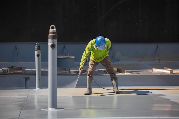 Top view male worker holding an industrial spray gun used for roof plate tank surface on steel industrial painting