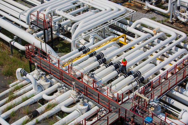 Top view male worker inspection at steel long pipes and pipe elbow valve in station oil factory during refinery valve of visual check record pipeline oil