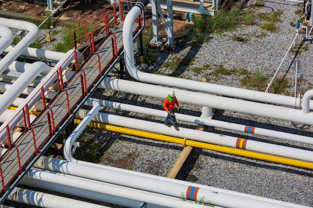 Top view male worker inspection at steel long pipes and pipe elbow valve in station oil factory during refinery valve of visual check record pipeline oil