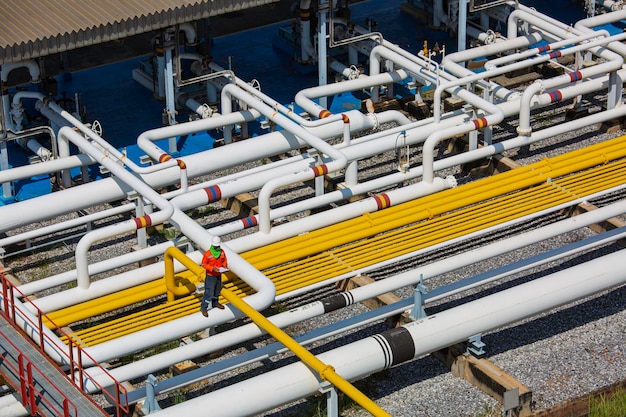 Top view male worker inspection at steel long pipes and pipe elbow valve in station oil factory during refinery valve of visual check record pipeline oil