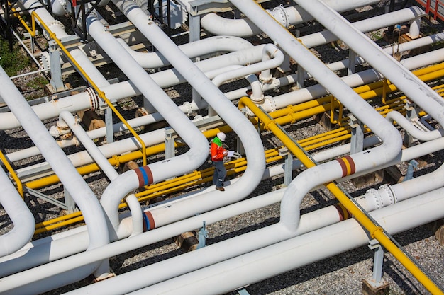 Top view male worker inspection at steel long pipes and pipe elbow valve in station oil factory during refinery valve of visual check record pipeline oil