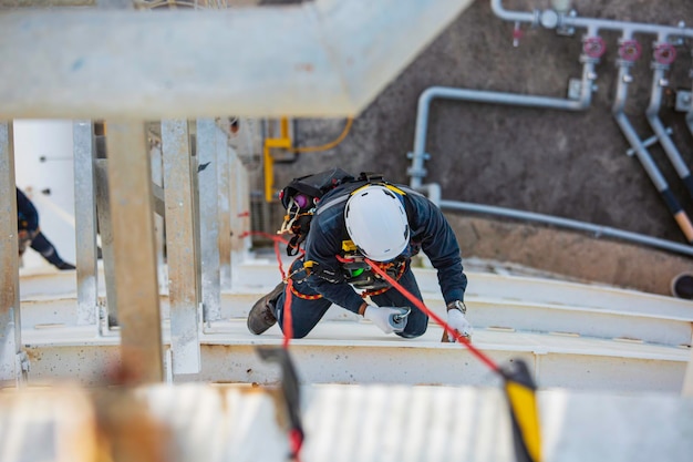 Top view male worker inspection wearing safety first harness rope safety line working at a high place on tank roof spherical